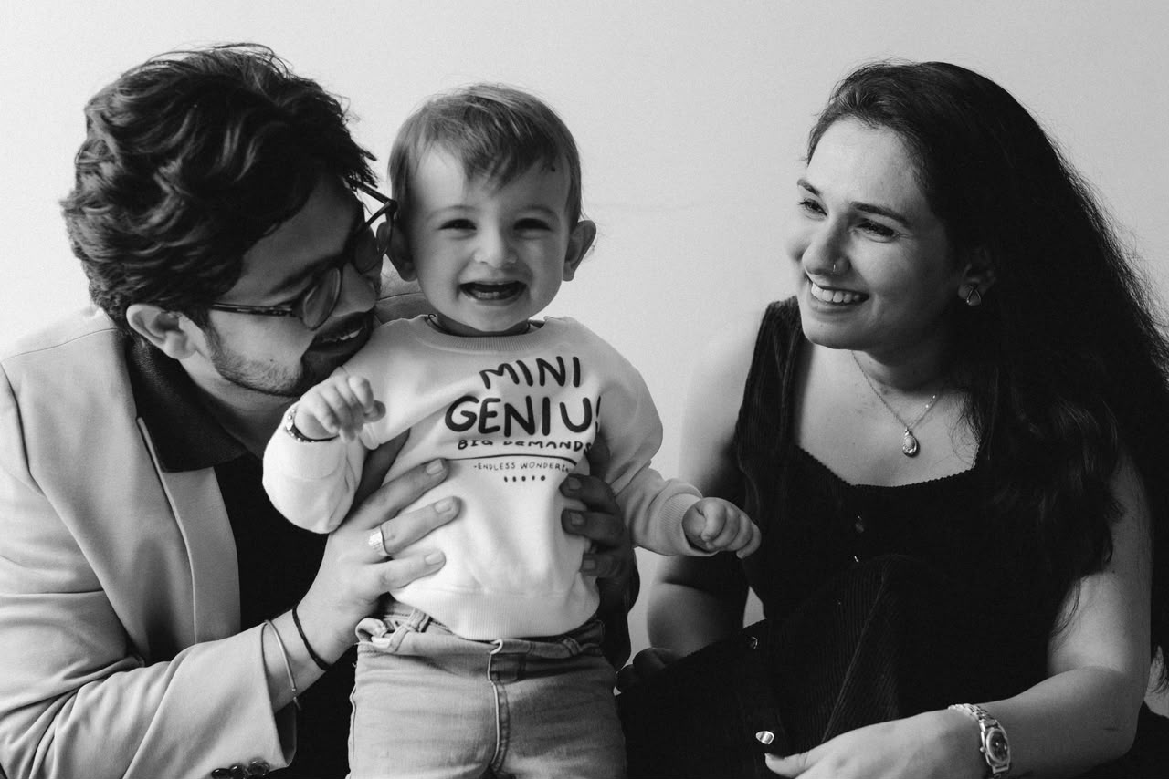 A smiling couple holding their laughing baby