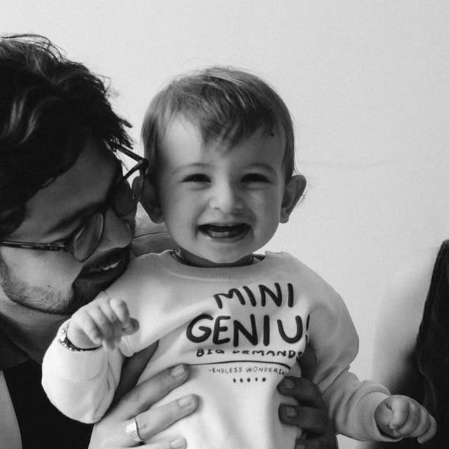 A laughing toddler in a white sweatshirt